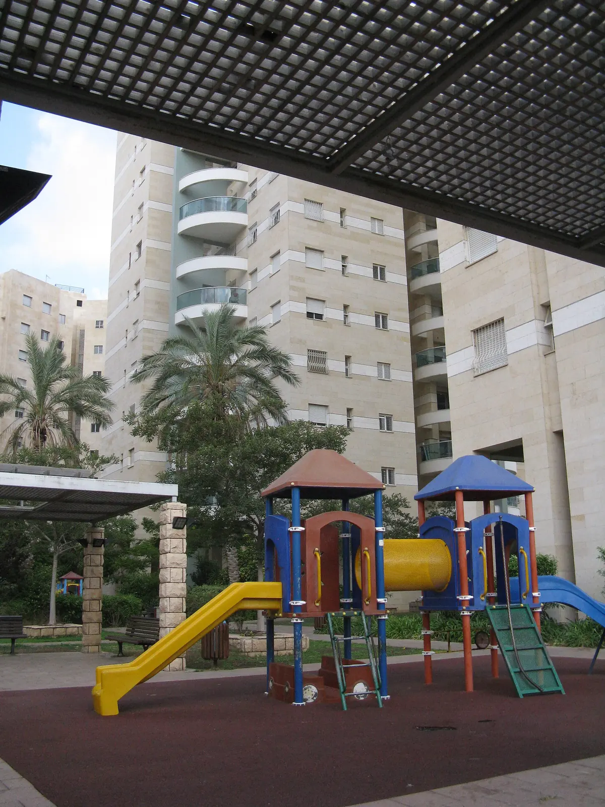 A shaded playground among residential towers in Givat Shmuel