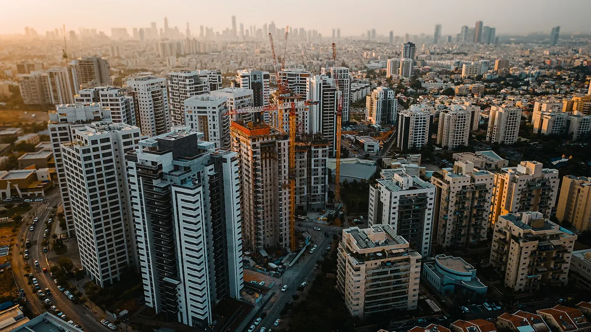 Aerial view of residential towers and construction cranes in Ramat Hadar, Givat Shmuel, with the Tel Aviv skyline behind
